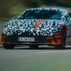 A camouflaged mercedes prototype drives towards the camera, there is motion blur