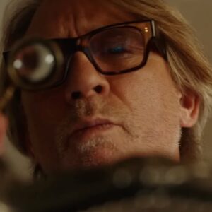 male detective in glasses looking at evidence through a monocle.