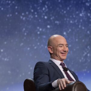 Jeff Bezos at a space conference, sitting in front of a picture of the stars in the night sky.