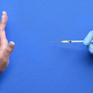 Vaccine refusal concept. Medic hand in glove with syringe. Hand refusing vaccination from measles or Covid-19. Anti-vaccination concept image with refusal gesture.