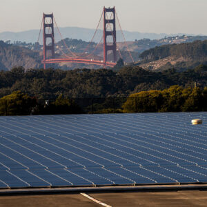 A hillside covered in solar panels, with the Golden Gate Bridge visible in the background.