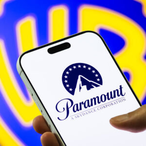 In this photo illustration, a smartphone displays the Paramount Skydance logo in front of a blurred Warner Bros. Discovery emblem, on December 6, 2025.