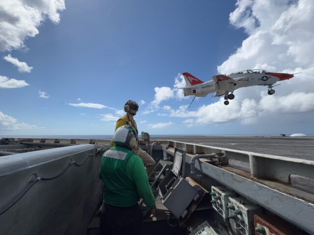 A T-45 touches down one the USS Eisenhower, its hook ready top catch the wire.