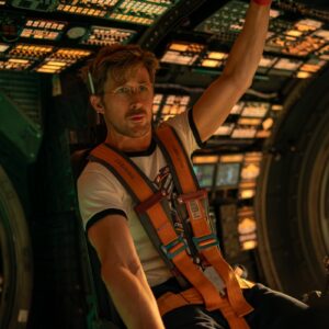 young blond man with mustache in ft shirt and parachute gear in the cockpit of an airplane