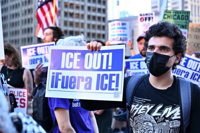 A protestor holds a sign that says "ICE OUT!"