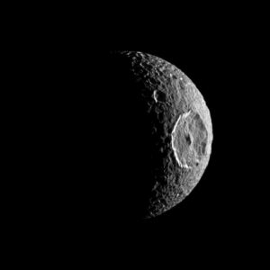 Image of a moon lit as a crescent with an absolutely enormous crater at its center.