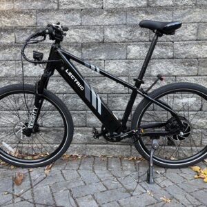 Image of a black metal bicycle against a grey stone wall.