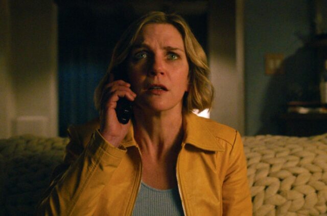 blond woman on cell phone in yellow jacket looking dismayed